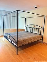 Full view of black wrought iron canopy bed frame in room