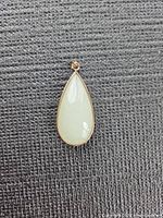 Front view of white jade teardrop pendant showing gold bezel and bail
