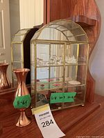 Closed brass-tone and glass curio cabinet on dresser