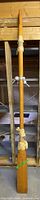 Full view of entire wooden oar standing upright showing overall condition