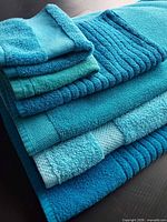 Stack of six turquoise and aqua towels showing varying sizes and borders