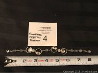 Swarovski crystal bracelet laid flat with measuring tape showing approximately 8 inches length and auction label