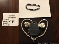 Photo showing Gloria Vanderbilt white faux pearl-like necklace laid out with matching clip-on earrings and a black and white faux pearl-like beaded bracelet.