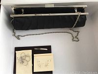 Overall lot including black pleated purse with silver chain and Gloria Vanderbilt necklace and earrings on branded cards, plus vintage knife brooch on a dark holder.