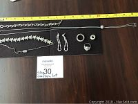 All jewellery items displayed on black background with measuring tape showing necklaces length.