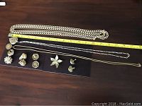 Vintage jewellery lot displayed on dark surface including various silver-tone necklaces, brooch, and multiple pairs of clip-on and screw-back earrings.