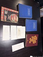 Top view of two blue albums, maroon Philatelia album, Universal Stamp Album, four labeled envelopes