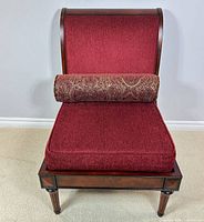 Front view of accent chair showing red upholstery, wood frame and bolster pillow