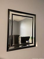 Full view of rectangular black framed mirror mounted on wall