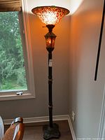 Full view of stained glass torchiere floor lamp beside window