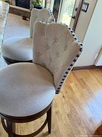 Front view of two upholstered barstools showing seats and tufted backs