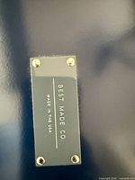 Close-up of brass plaque on lid showing brand