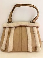 Front view of tan suede-like handbag with faux fur strips and strap visible
