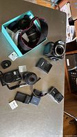 Group shot showing DSLR body, two PowerShot cameras, two EF lenses, chargers, batteries and strap