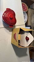 Heart-shaped red stoneware cocotte with lid on tabletop next to box