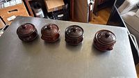 Four brown glazed stoneware jars with lids, side view