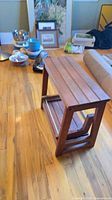 Oblique view of wooden two-step slatted stool on wood floor