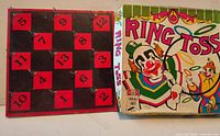 Game board with numbered hooked squares alongside box lid with circus clown graphics