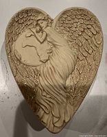 Lid top showing sculpted angel embracing globe with wing and glitter detail