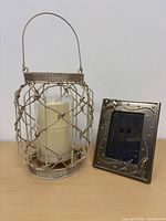 Lantern, pillar candle inside, and photo frame side by side