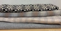 Four folded bolts of patterned wool fabric stacked