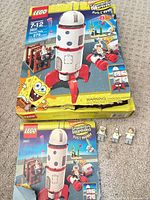 Damaged LEGO Rocket Ride box, instruction booklet and three minifigures displayed