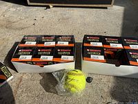 Two unopened six-packs of fastpitch softballs, one loose wrapped ball in foreground