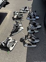 All seven skate pairs and two pucks laid on asphalt