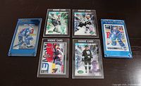 All six hockey cards in holders laid out on table