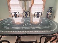 Full view of table with three chairs, showing glass top and inlay detail