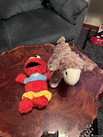 Elmo plush and lamb plush on wooden table