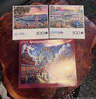 Front view of three sealed puzzle boxes showing artwork and piece counts