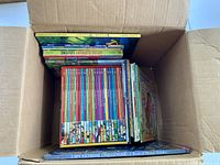 Box with large stack of slim hardcovers and other books