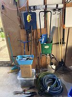 Wide view of lot showing hoses, seeder, sprayer, rakes, hand tool bin