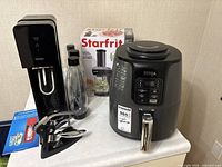 Group shot: Ninja air fryer, SodaStream machine with bottles, Starfrit spiralizer box, OGGI wine opener
