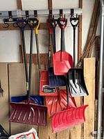 Multiple snow shovels hanging on wall rack