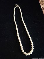 Full view of graduated pearl necklace laid flat