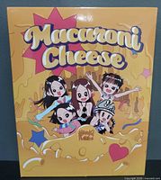 Front of yellow/orange slipcase with Macaroni Cheese title and cartoon characters