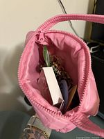 Open pink quilted pouch showing interior contents like boxed item and jewelry