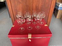 Seven clear stemmed wine glasses displayed on red box front view