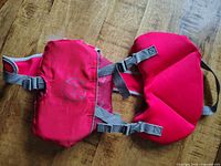 Front view of red infant PFD fully laid out showing grey buckle straps