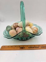overall view of glass basket filled with stone eggs next to ruler