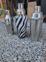 Front view of three cocktail shakers showing styles, materials, and condition