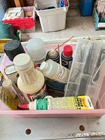 Pink bin holding assorted aerosol cans, bottles and adhesive tube