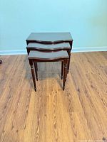 Front view of three stacked nesting tables on wood floor