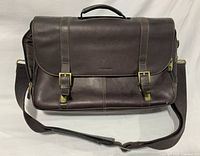 Front view of brown leather Samsonite briefcase showing flap, buckles, handle and shoulder strap