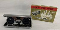 Folding sport glasses open, box standing behind