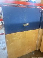 Front view of blue/natural plywood cabinet showing latch and wear