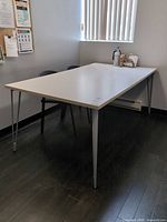 Entire table showing top surface, legs, surrounding chairs for scale