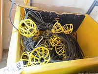 Large yellow bin filled with black-cabled work-light strings and yellow cages